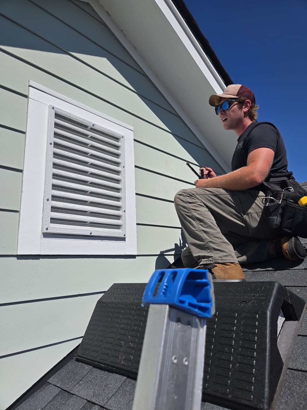 A Monster Wildlife technician on a ladder screening a gable vent to keep wildlife out of a Charleston home